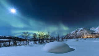 Snow covered field green aurora - a mountain range in the background free wallpaper