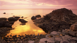 Rocky beach sunset cityscape water - a sunset in the background free wallpaper for desktop