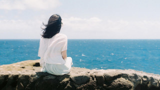 Woman sitting rock ocean cliff - a rock free wallpaper for desktop