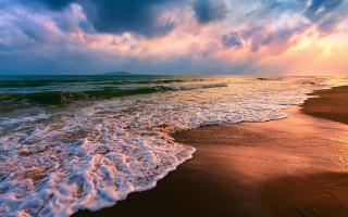 Beach waves cloudy sunset cityscape - a sunbeam in the distance free wallpaper