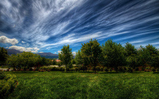 Field trees clouds house mountains - a house in the distance free wallpaper