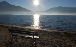 Beach bench mountains ocean sunlight - the background and the ocean in the foreground free wallpaper