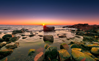 Sunset rocky beach boat mountain 3 - a large rock formation in the foreground free wallpaper