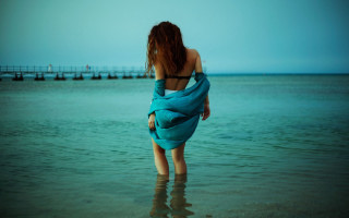 Woman blue towel beach sea - a pier in the background free wallpaper