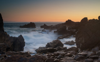 Rocky beach wave sunset clouds - the shore and a sunset in the background free wallpaper