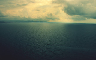 Moody ocean sunset cloudy horizon - a boat in the distance free wallpaper