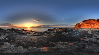 Sunset rocks water mountains city - a sunset over a body of water free wallpaper