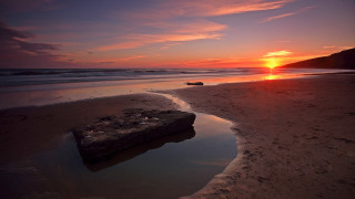 Rock sand beach sunset ocean - orange sun free wallpaper