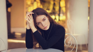 Serious woman table brown eyes - a woman sitting free wallpaper