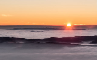 Sunset mountain range foggy valley - a few cloud below free wallpaper for desktop