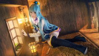 Blue haired woman cosplay sitting - a bed in a room free wallpaper