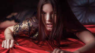 Woman laying bed red sheet - a black background behind her free wallpaper