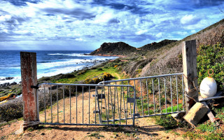 Gated ocean beach rocks cityscape - area free wallpaper