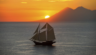 Sailboat ocean sunset mountains clouds - orange sky free wallpaper