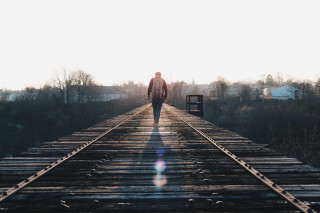 Man walking train track sunshine - liminal free wallpaper