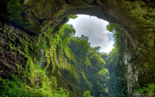 Cave entrance waterfall lush green - a waterfall in the middle of it free wallpaper