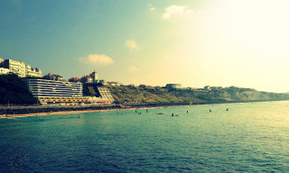 Beach large building people swimming - the water below free wallpaper
