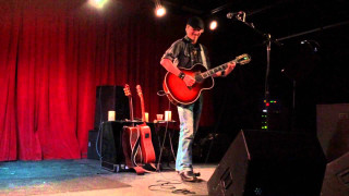 Man stage guitar microphone performance - a red curtain behind free wallpaper
