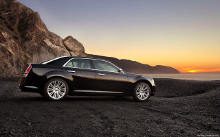 Black car rocky beach sunset - a mountain in the background and a body of water free wallpaper
