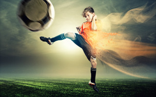 Young boy kicking soccer ball - a soccer ball free wallpaper