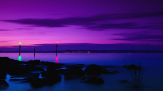 Purple blue sky lighttower rocks - the foreground and a body of water free wallpaper for desktop