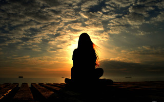 Woman sitting dock sunset ocean - the sky above her free wallpaper