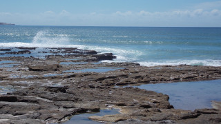 Person walking rocky beach surfboard - panoramic free wallpaper for desktop