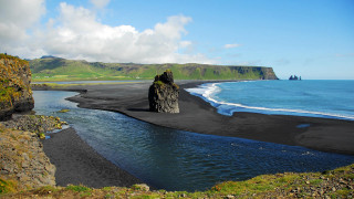 Black sand beach rock formation 2 - a rock formation in the middle of it free wallpaper