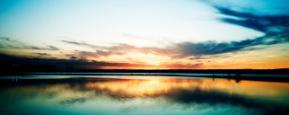 Sunset water clouds people shore - a sunset over a body of water free wallpaper