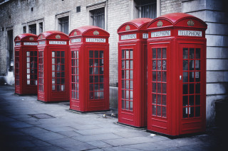 Red telephone booths brick building - a sidewalk in front free wallpaper