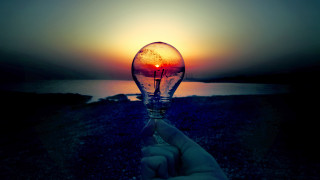 Hand lightbulb sunset water background 2 - a sunset in the background and a body of water free wallpaper