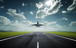 Jetliner flying cloudy sky runway 2 - a green field below free wallpaper