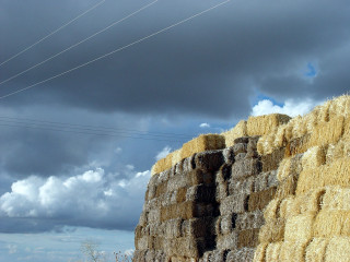 Haystack field clouds powerlines pole - a field under a cloudy sky free wallpaper