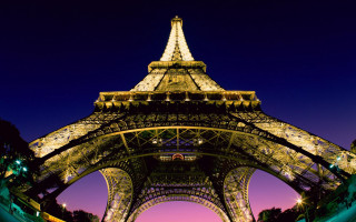 Eiffel tower lit night pink - a blue sky in the foreground free wallpaper