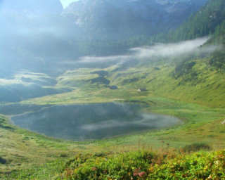 Grassy field lake mountains fog - a lake in the middle of it free wallpaper for desktop