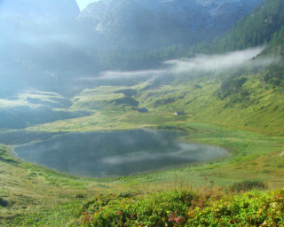 Grassy field lake mountains fog 2 - a lake in the middle of it free wallpaper for desktop