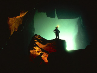 Man standing cliff cave flashlight - a flashlight free wallpaper