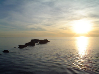 Sunset ocean rocks sky clouds - the sun in the distance behind free wallpaper