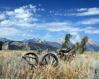 Field wooden wheels mountains clouds - the middle of it free wallpaper for desktop