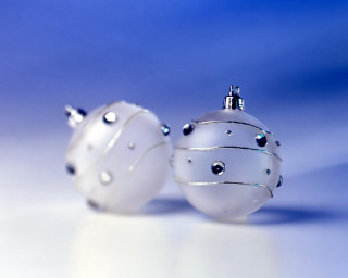 Two white ornaments sitting on 2 - a table together free wallpaper